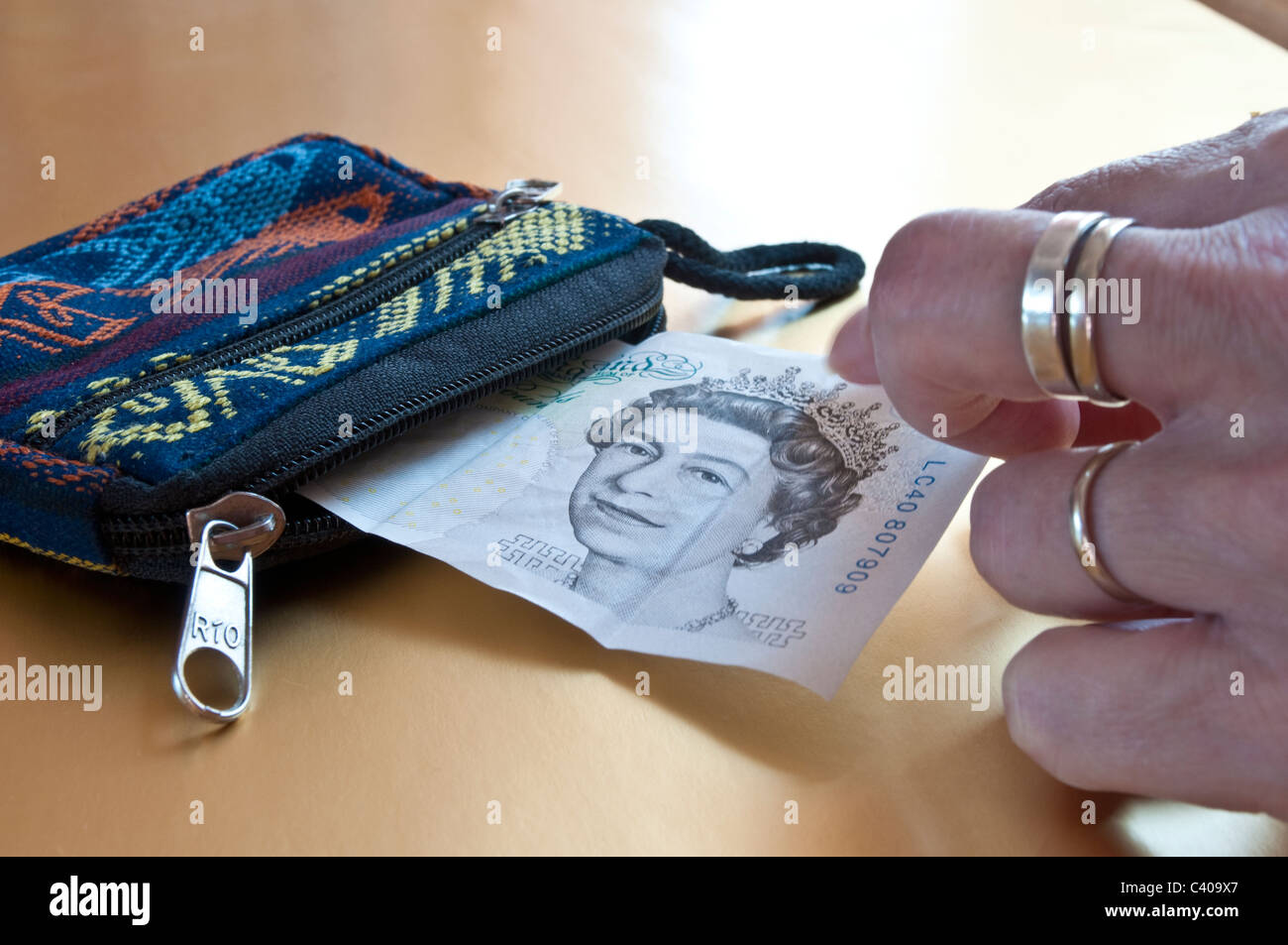 Zarte Frauenhand Einnahme sorgfältig eine fünf-Pfund-Note aus der Handtasche Stockfoto