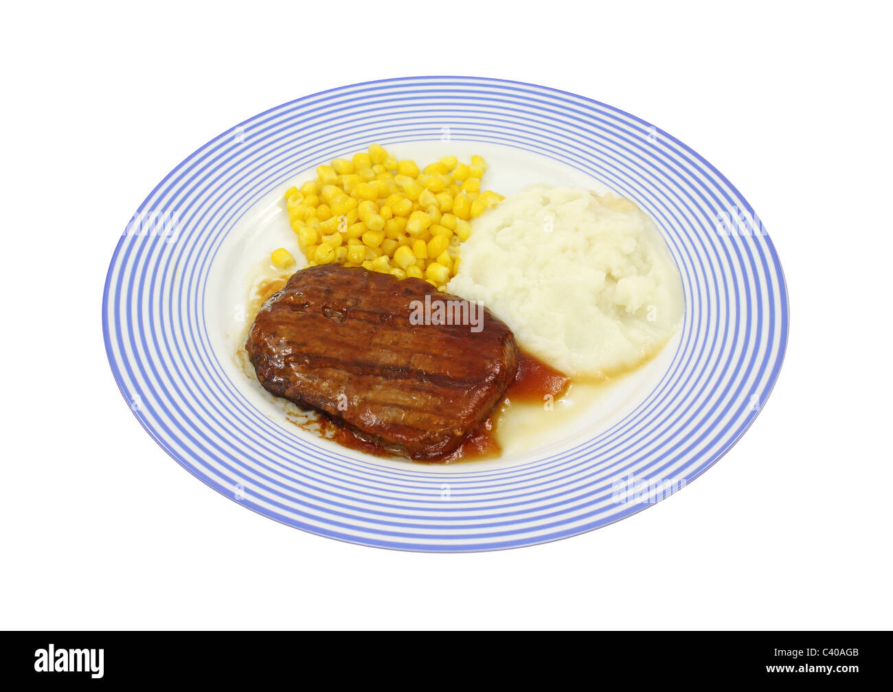 Salisbury Steak Essen mit Mais und Kartoffeln auf einem blau gestreiften Teller. Stockfoto