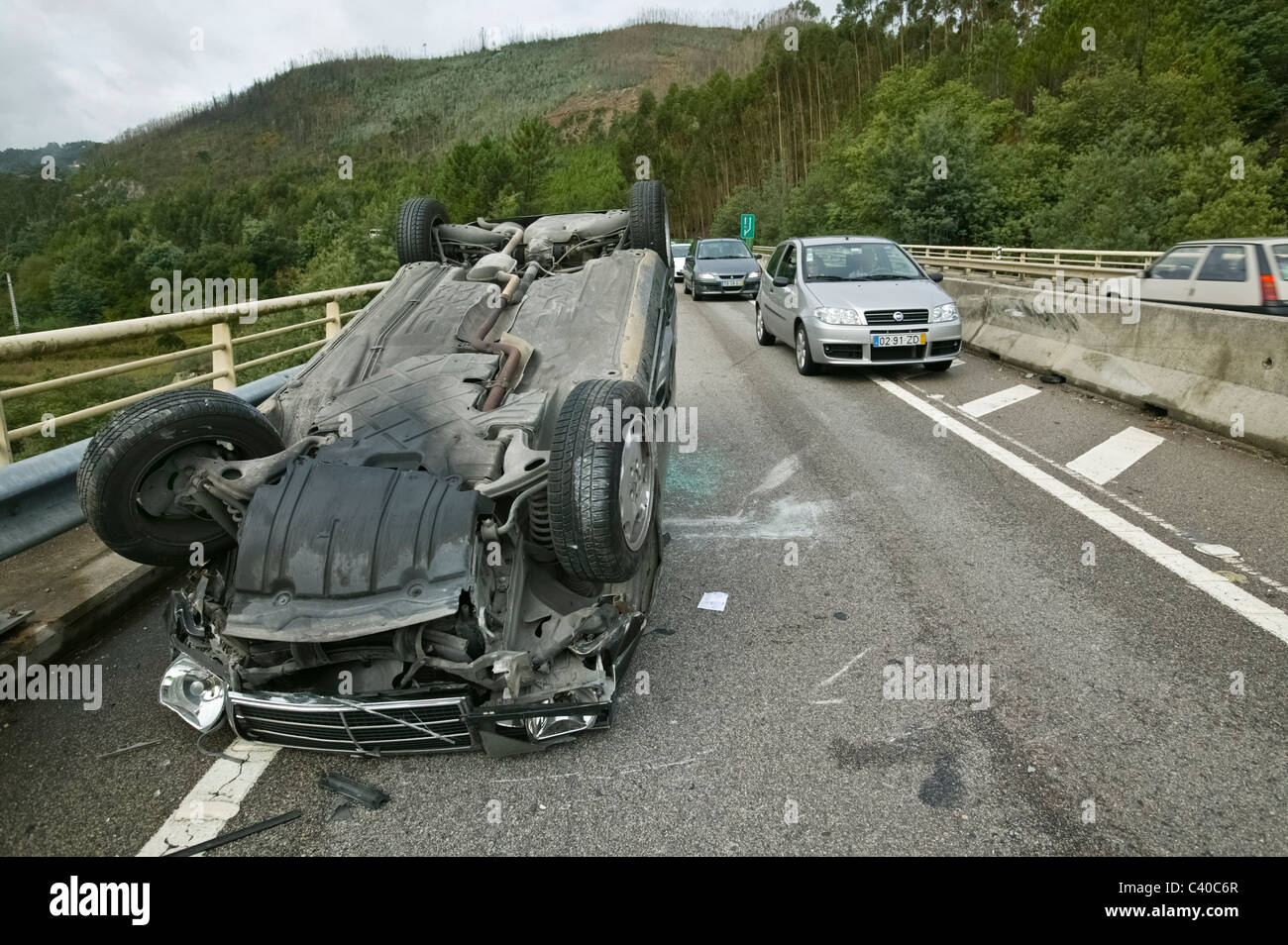 Autos fahren durch ein anderes zerstörten und umgestürzten Auto in Zentralportugal IP3 unterwegs nach einem Autounfall Stockfoto