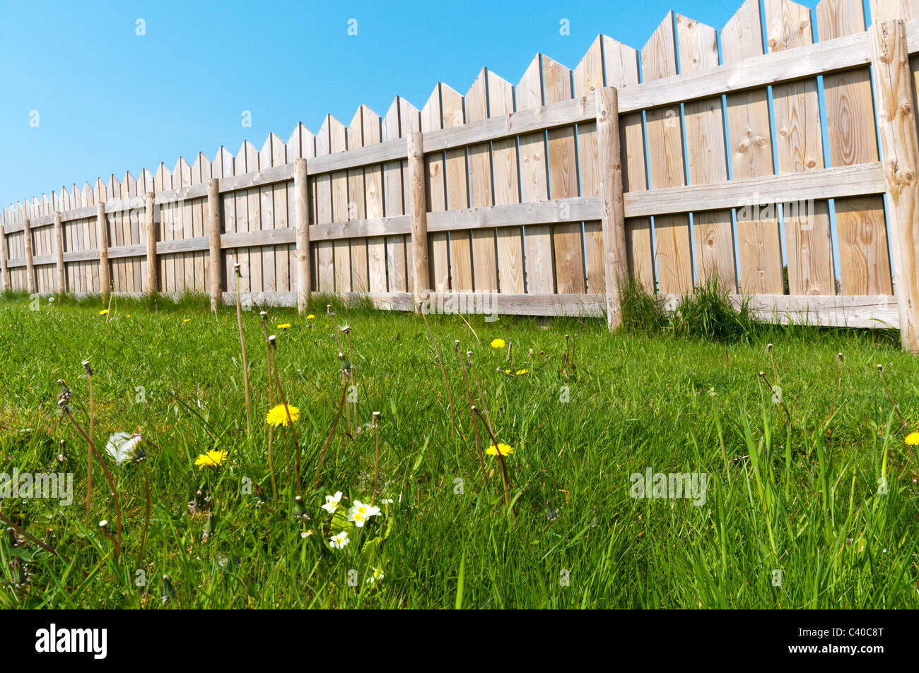 Ein hölzerner Gartenzaun vor einem klaren blauen Himmel zu sehen. Stockfoto