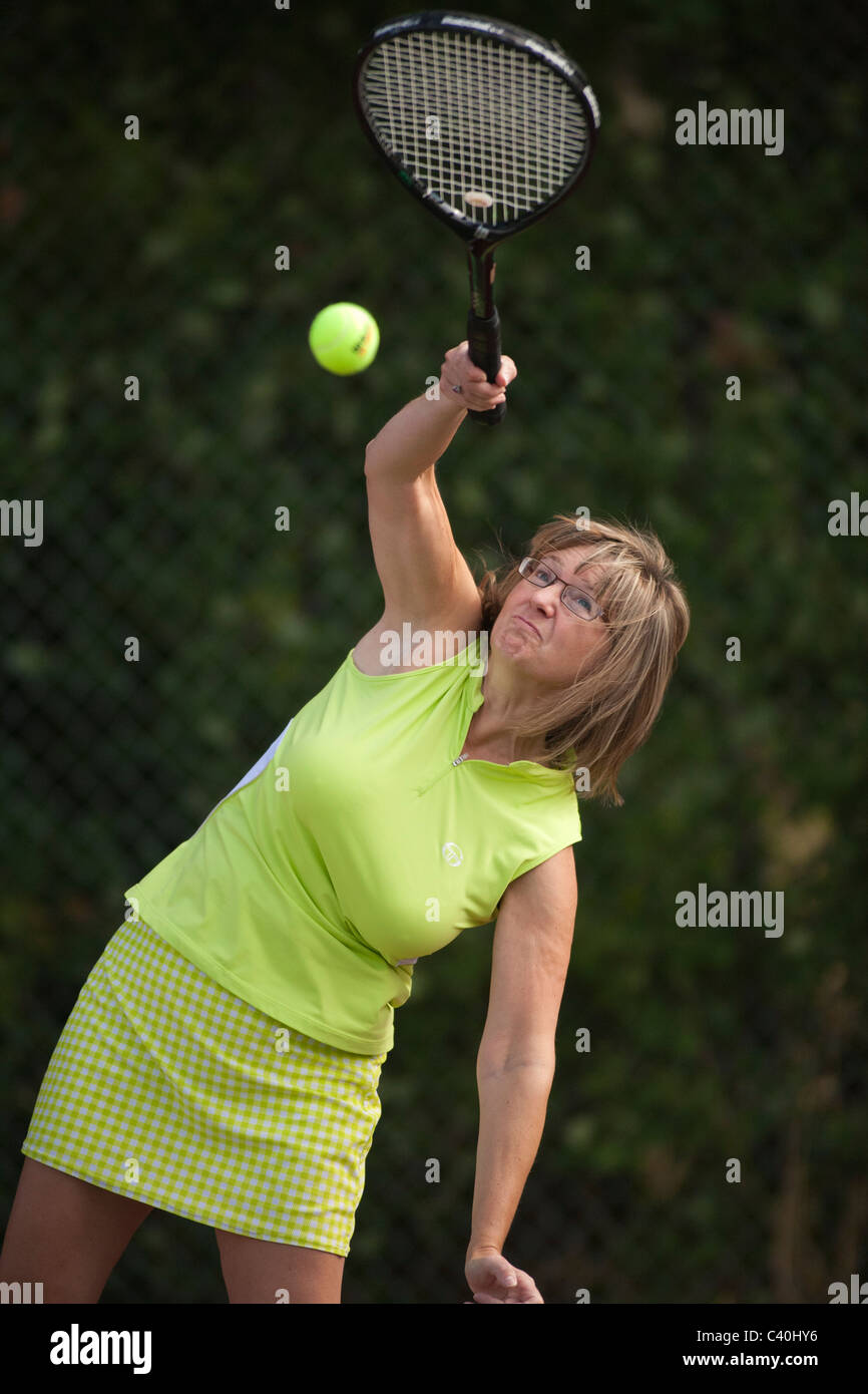 Frau serviert Tennisball während Spiel-Victoria, British Columbia, Kanada.  Hinweis-Tennisball Digital hinzugefügt. Stockfoto