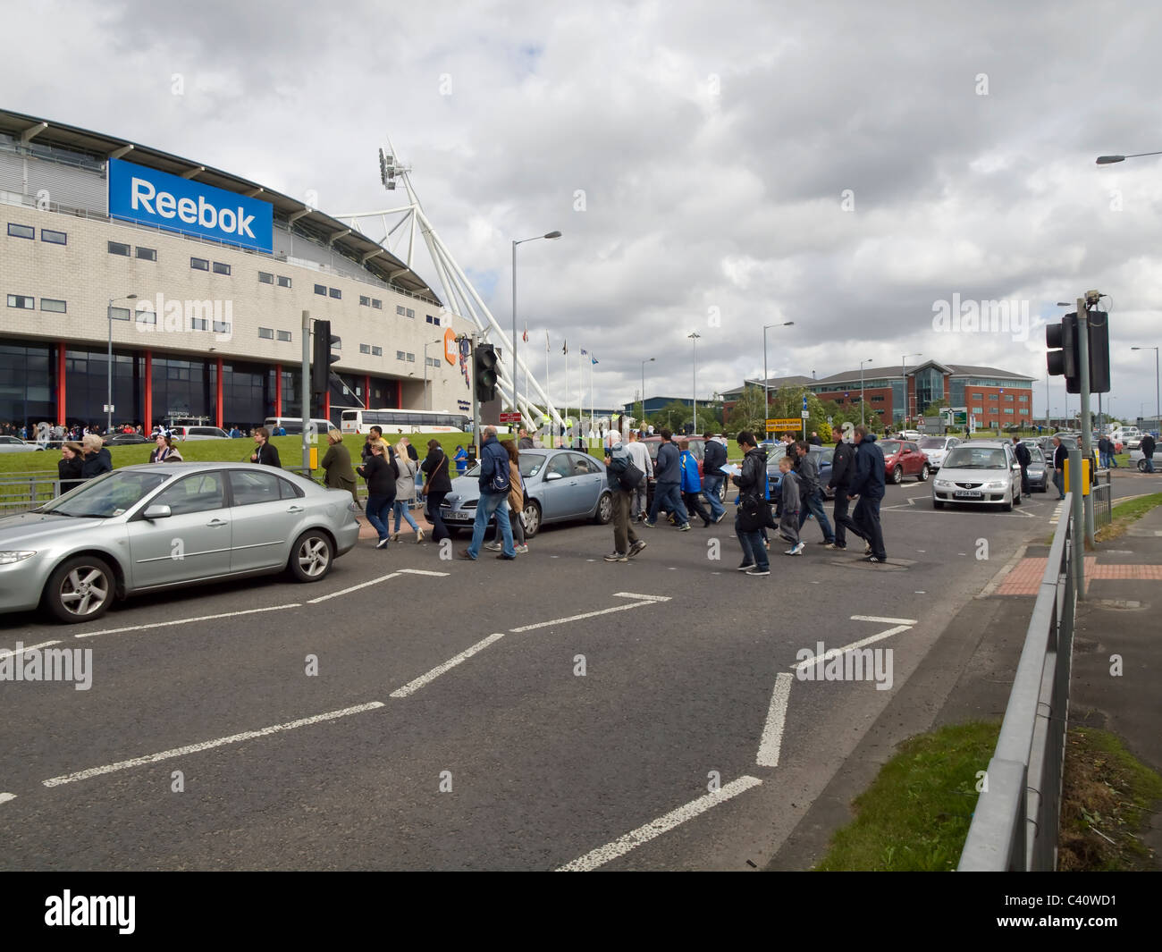 Fußball-Fans über die Straße gehen, um das Spiel im Reebok Stadium, das Heimstadion von Bolton Wanderers Football Club. Stockfoto