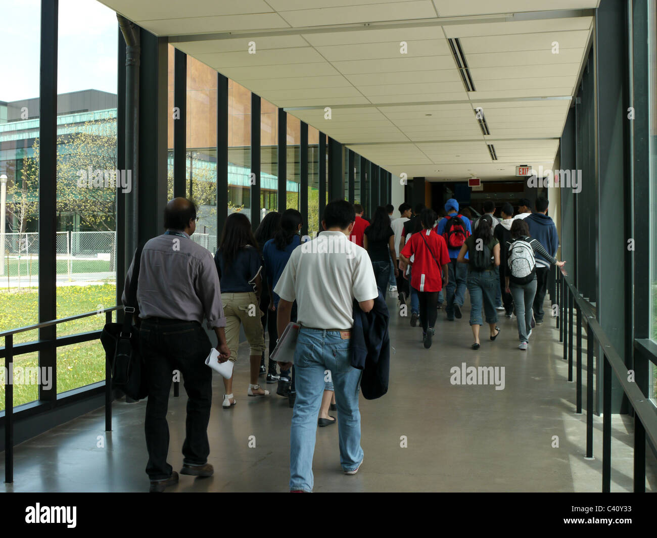 Studenten, die zu Fuß in ummauerten Glaskorridor Stockfoto