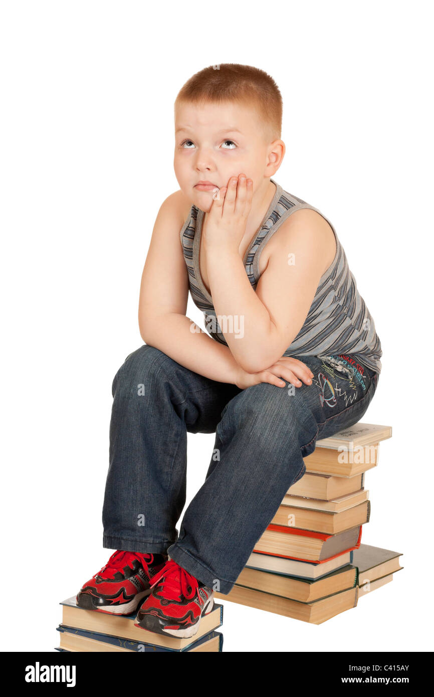Junge sitzt auf den Büchern der seinen Kopf in seine Hände, die isoliert auf weißem Hintergrund Stockfoto