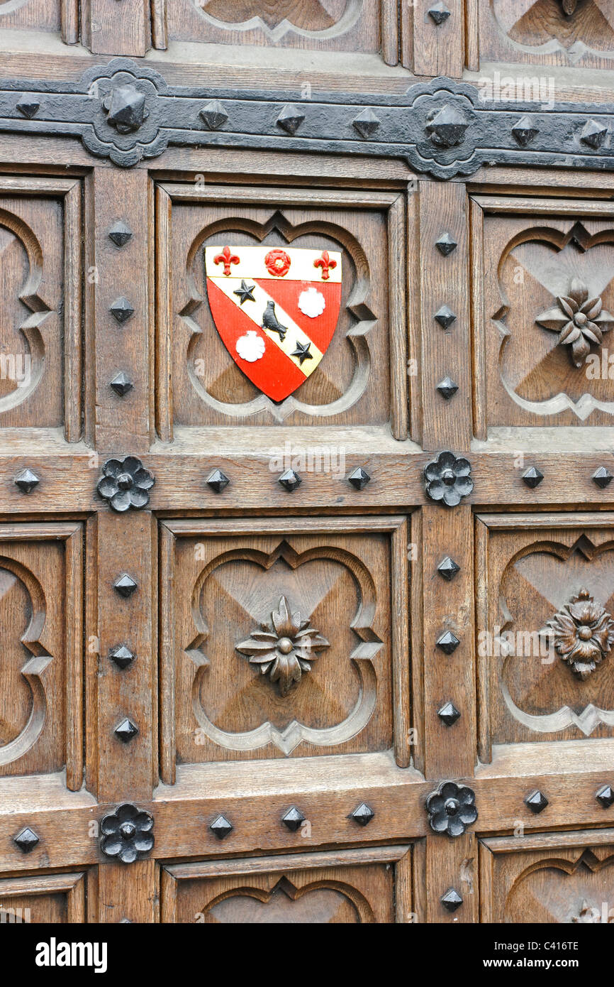 Eine alte Eisen gebänderten Eichentür in der Universitätsstadt Oxford, England mit einem College-Wappen Stockfoto