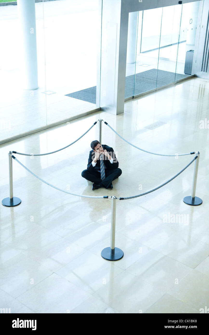 Geschäftsmann, sitzen am Boden im Inneren abgesperrt Bereich in der lobby Stockfoto