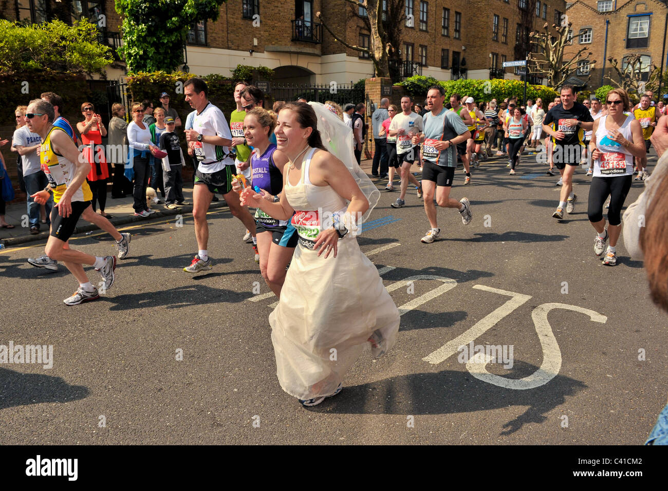 Läufer teilnehmen in der Jungfrau 2011 London-Marathon, gesehen hier bei 14 Meilen an einem sehr heißen Tag mit einer Dame in einem Brautkleid Stockfoto