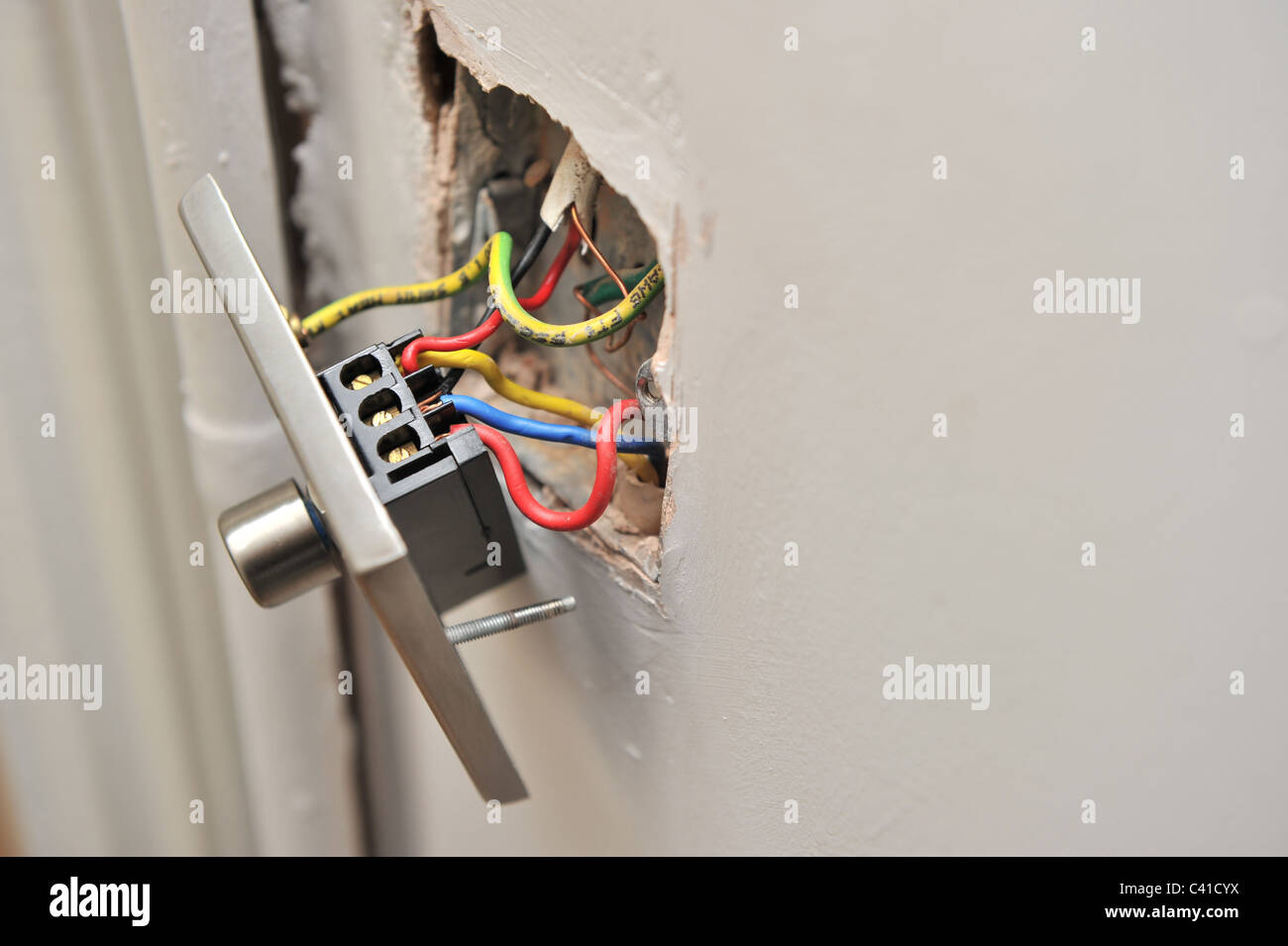 eine fehlerhafte Haus Licht dimmer-Schalter von Wand zeigt elektrische weggezogen Drähte parallel während DIY Stockfoto