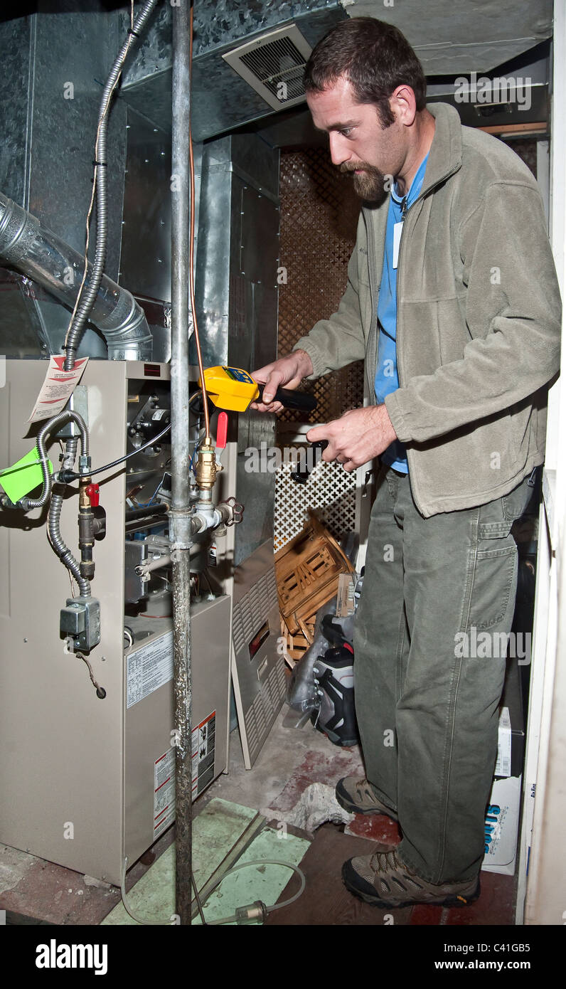 Ein Techniker überprüft die Heizung für Undichtigkeiten während einer grünen Blöcke Energie-Audit. Stockfoto