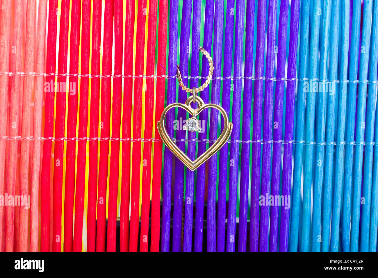 Herz-Anhänger aus Gold auf farbigem Hintergrund Stockfoto