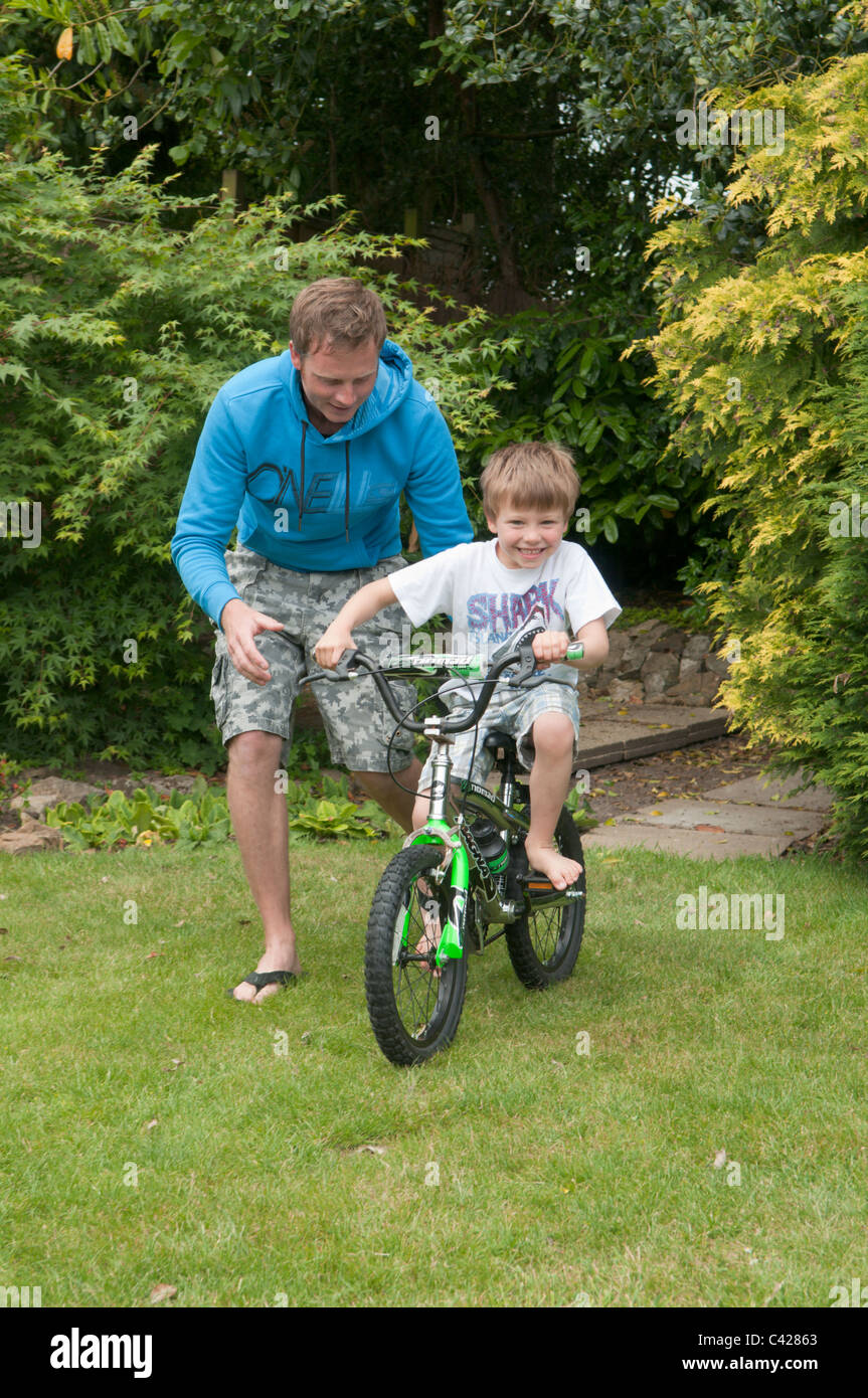 Vater im Garten hinter dem Haus seinen Sohn beizubringen, mit dem Fahrrad Stockfoto