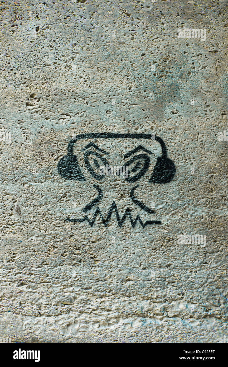 Graffito auf einer grauen Wand zeigt ein Kopf mit großen Augen das Tragen von Kopfhörern. München, Deutschland Stockfoto