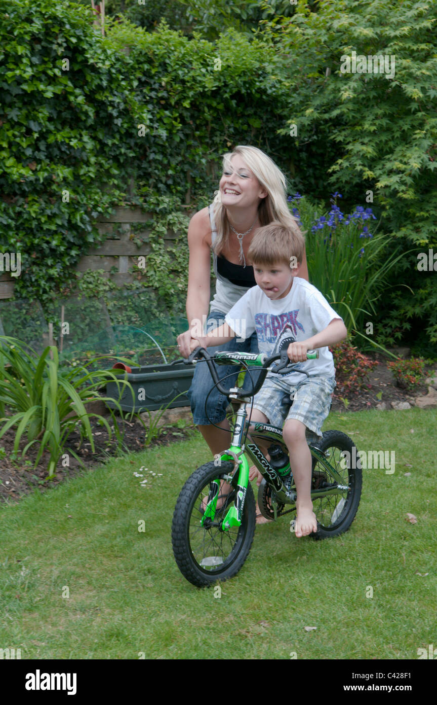 Mutter im Garten hinter dem Haus ihres Sohnes beizubringen, mit dem Fahrrad Stockfoto