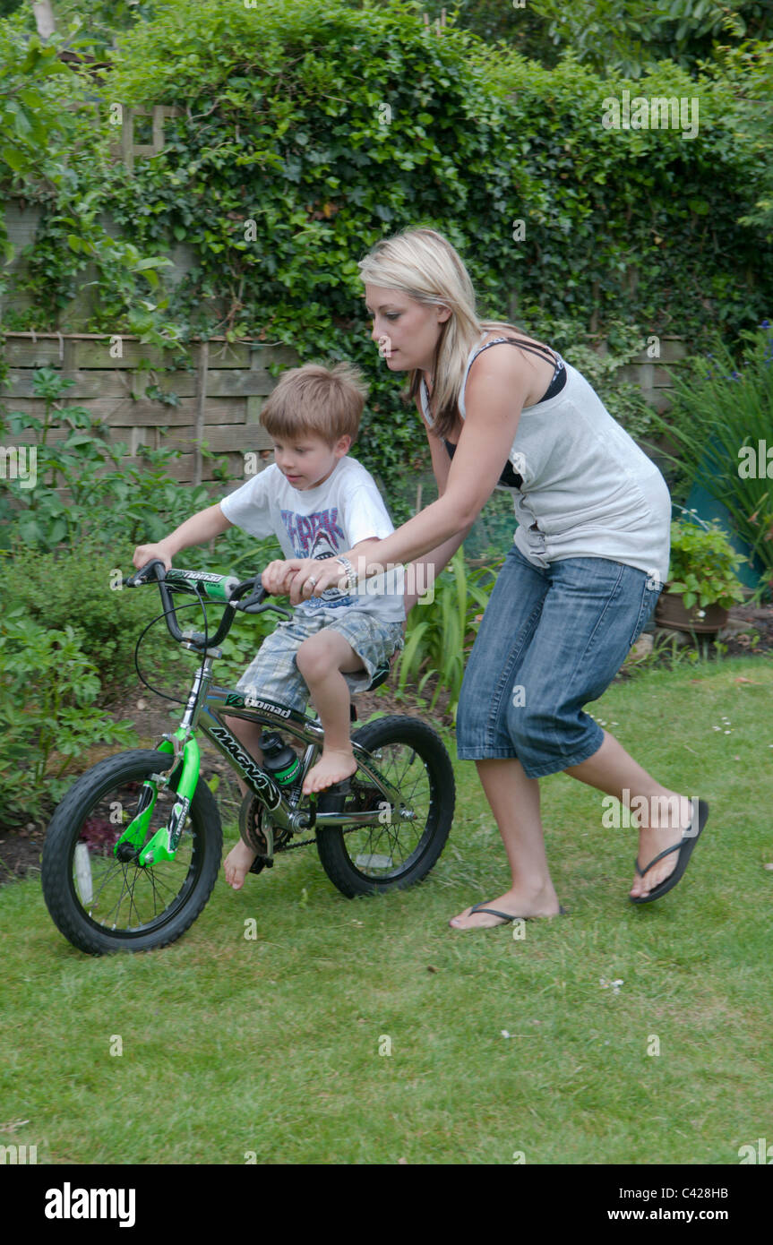 Mutter im Garten hinter dem Haus ihres Sohnes beizubringen, mit dem Fahrrad Stockfoto