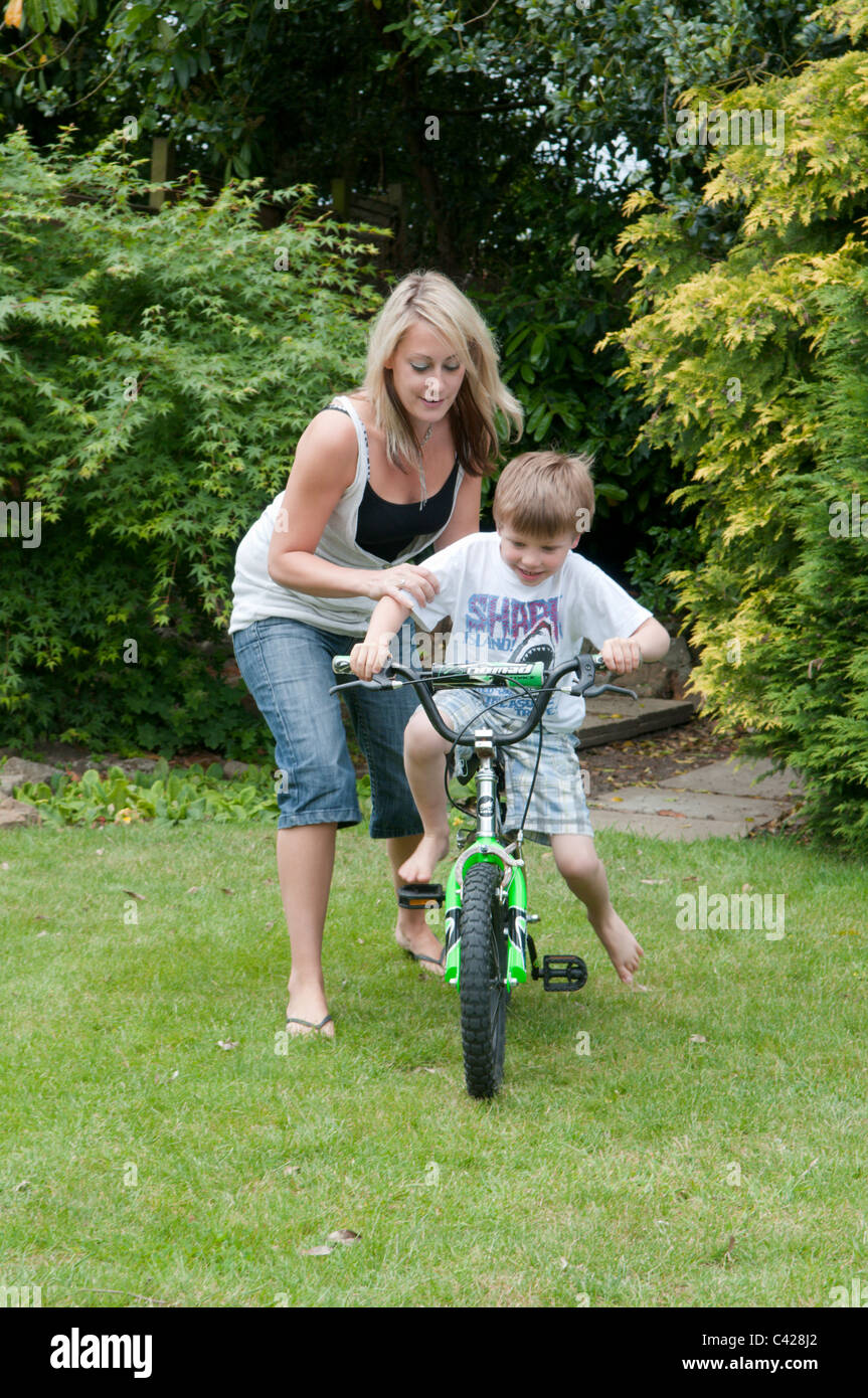 Mutter im Garten hinter dem Haus ihres Sohnes beizubringen, mit dem Fahrrad Stockfoto