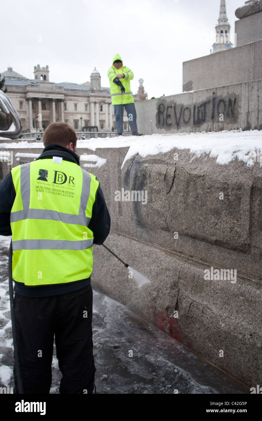 Graffiti aus studentischen Proteste wird von Nelson Säule vor Weihnachtsbaum Beleuchtungszeremonie auf dem Trafalgar Square gereinigt. Stockfoto