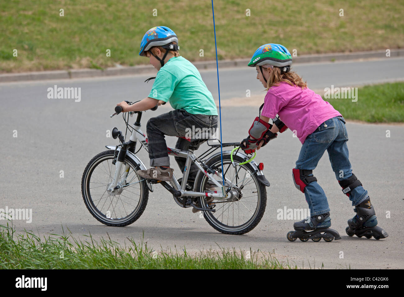 kleiner Junge auf seinem Fahrrad ziehen seine Schwester auf Inline - Skates  hinter ihm Stockfotografie - Alamy