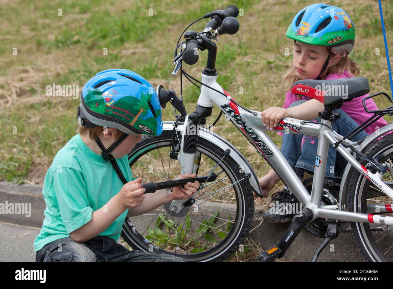 kleiner Junge seinen Fahrradreifen, seine Schwester beobachtete ihn aufblasen Stockfoto