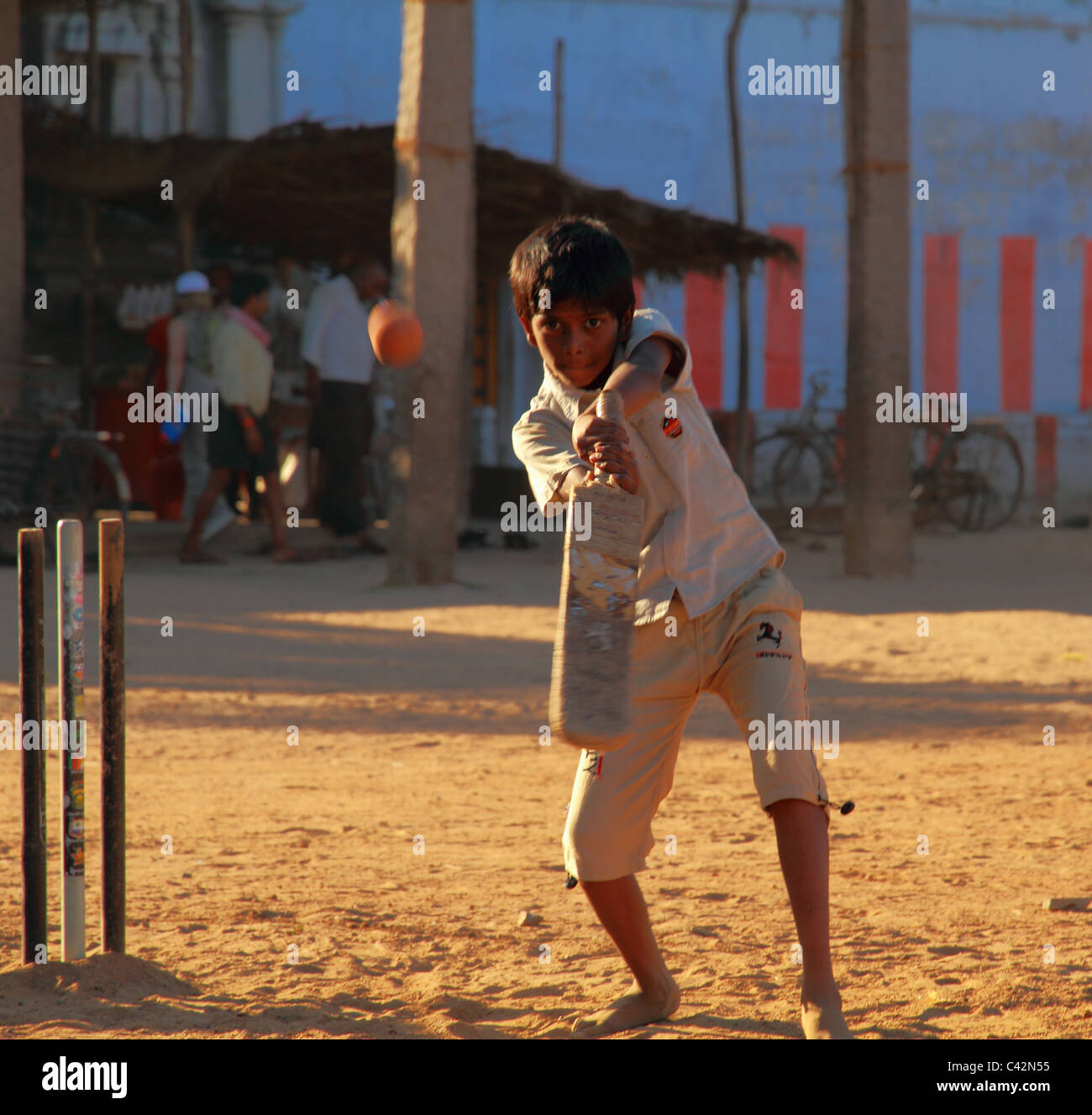 Indianerjunge schlagen Cricketball bei Sonnenuntergang Stockfoto