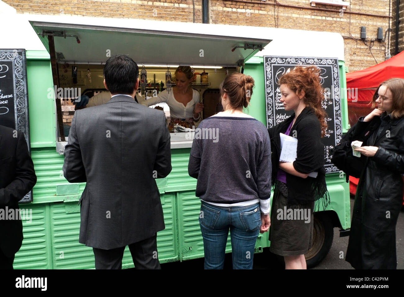 Kunden kaufen Essen zur Mittagszeit von Luardo grünen van Whitecross Street Market in der Nähe der Barbican London UK KATHY DEWITT Stockfoto