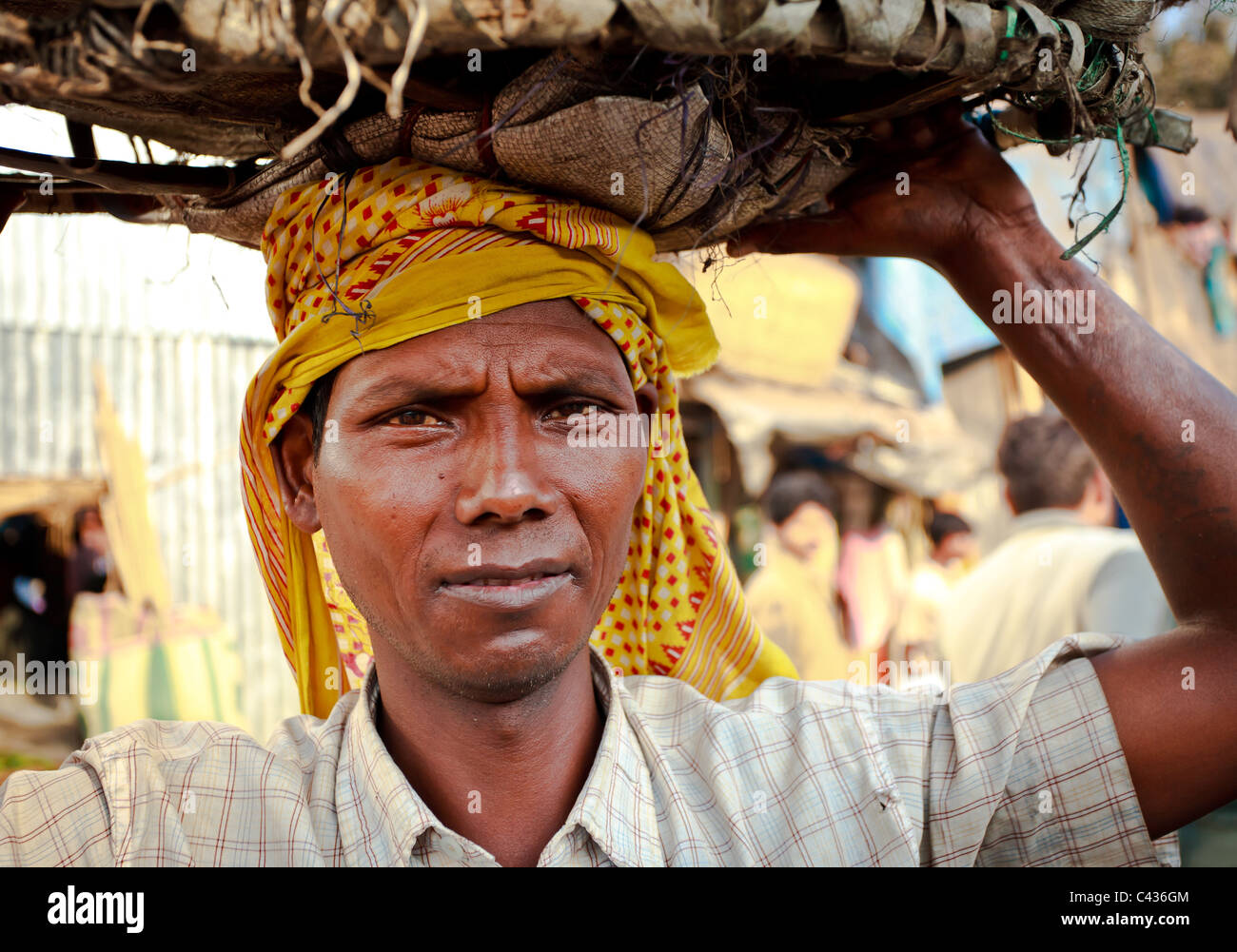 Porträt der Arbeiter mit einem Korb auf dem Kopf aus dem Malik Ghat Blumenmarkt in Kolkata, West Bengal, Indien Stockfoto