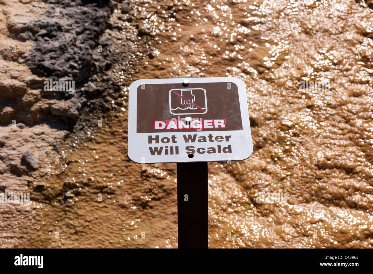 Warnschild im Yellowstone National Park lesen wird Heißwasser verbrühen. Kochend heißes Wasser läuft über Felsoberfläche. Stockfoto
