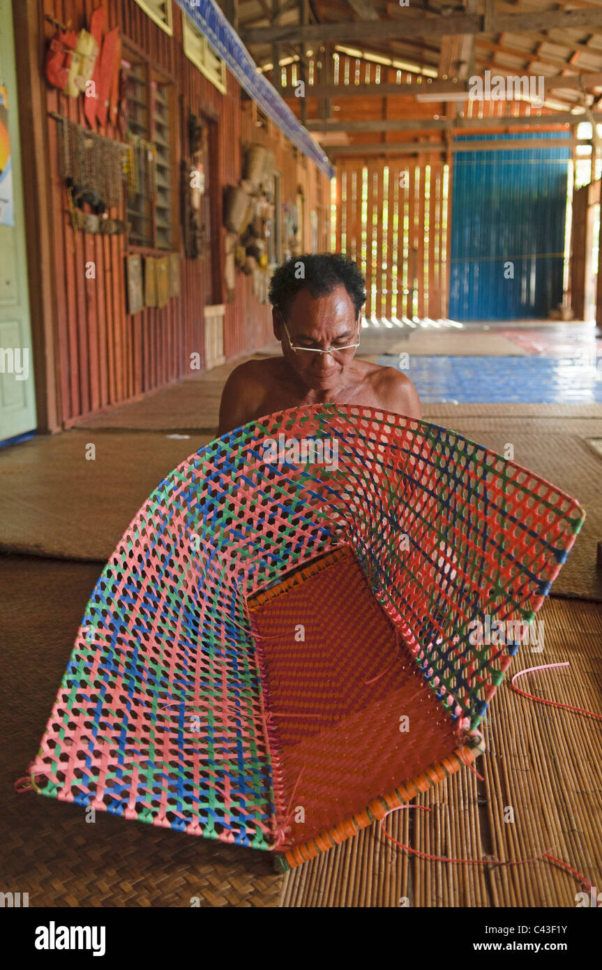 IBAN Mann weben einen Korb in den Nanga Sumpa Langhaus in Sarawak, Borneo, Malaysia Stockfoto