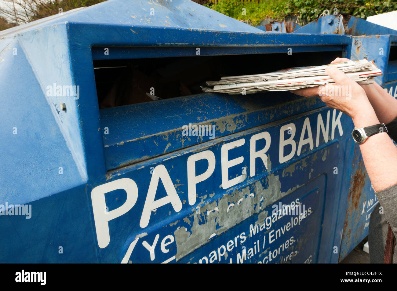 Eine Frau, die recycling-Zeitungen in einer großen bank Stockfoto