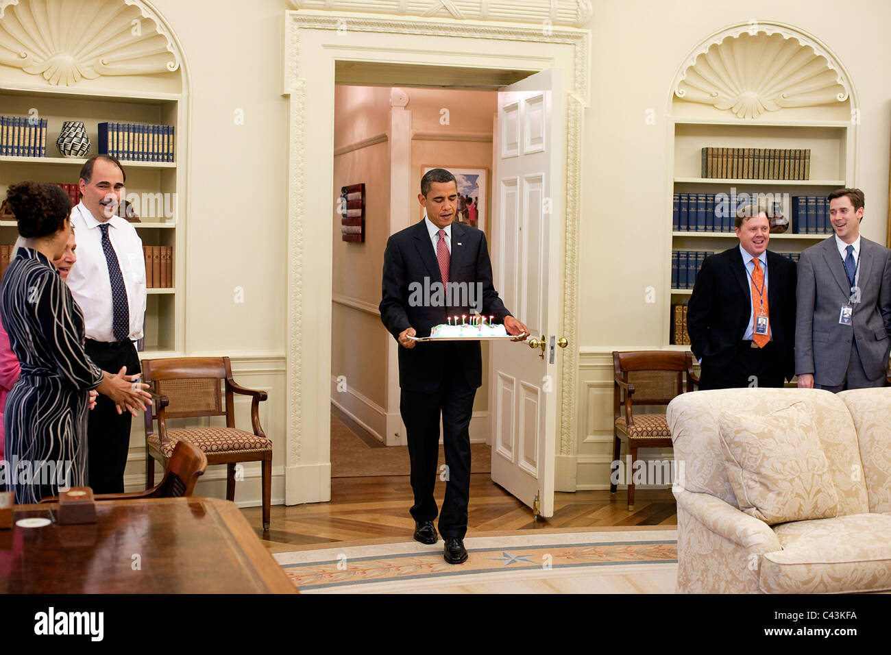 Präsident Barrack Obama trägt einen Kuchen in das Oval Office-Geburtstagsparty für Phil Schiliro Stockfoto
