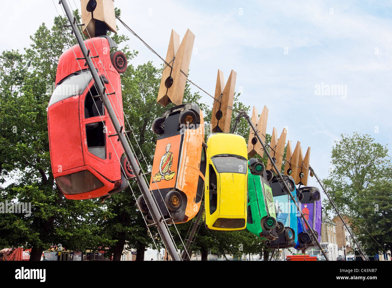 Sieben Autos hängen von riesigen Wäscheklammern auf einem Draht in Brighton im Rahmen der jährlichen Kunst Festival Fringe Straßentheater. Stockfoto Sieben Autos hängen von riesigen Wäscheklammern auf einem Draht in Brighton im Rahmen der jährlichen Kunst Festival Fringe Straßentheater. Stockfoto