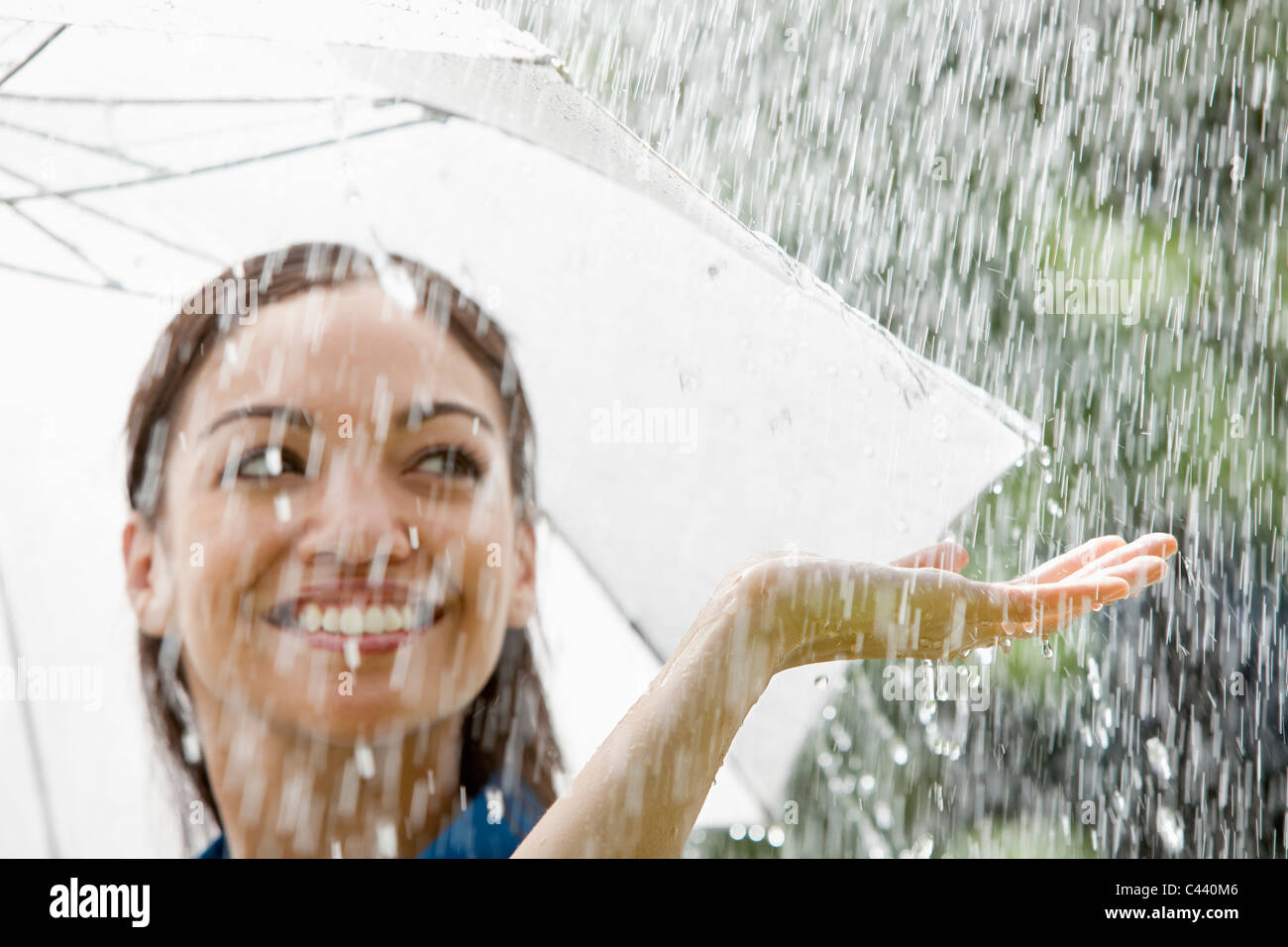 Schöne spanische Frau hält Regenschirm draußen im Regen Stockfoto