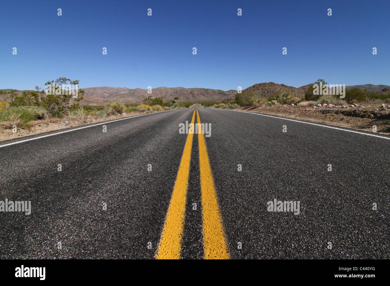 Ein Blick auf die offene Straße durch eine weite leere Wüste laufen. Stockfoto
