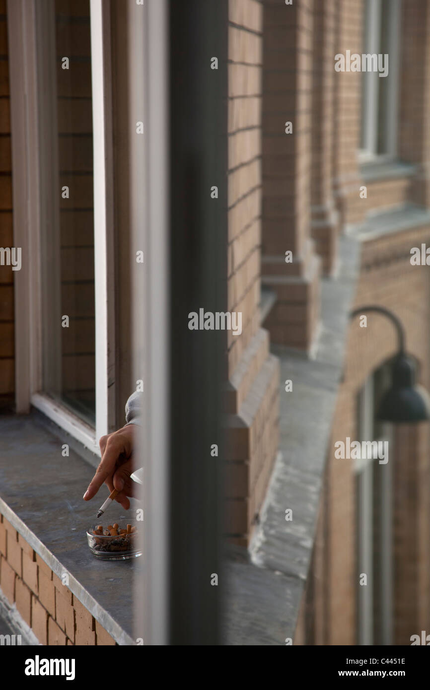 Detail der eine Person das Rauchen aus dem Fenster Stockfoto