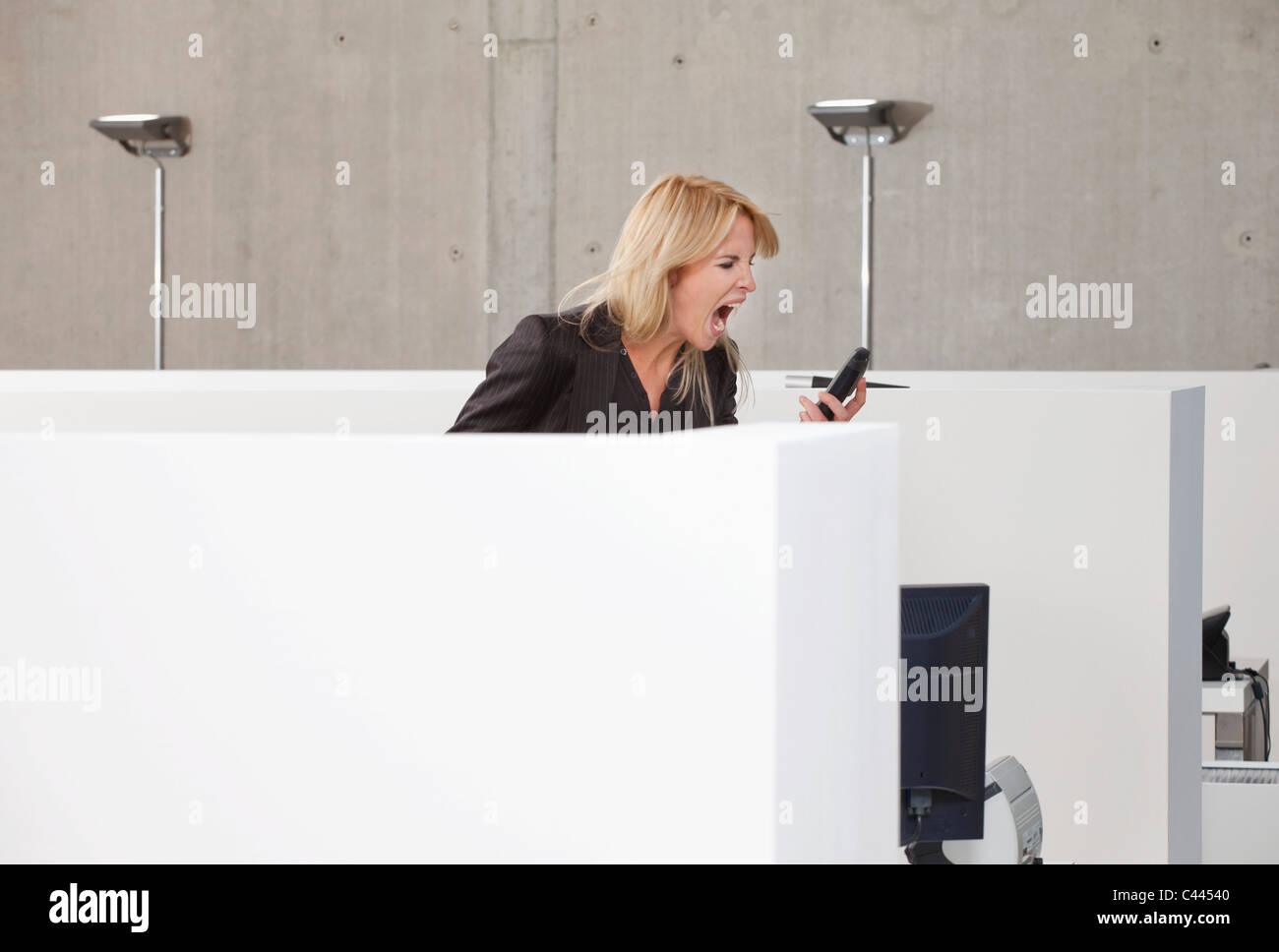 Eine Frau schreit in einem Mobiltelefon in einem Großraumbüro Stockfoto