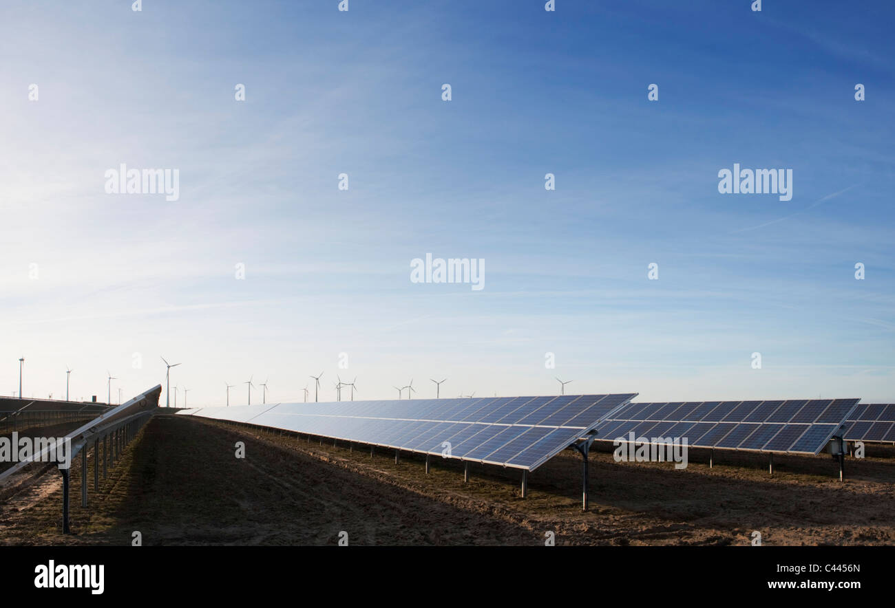 Sonnenkollektoren in ein Feld und Windturbinen in der Ferne Stockfoto