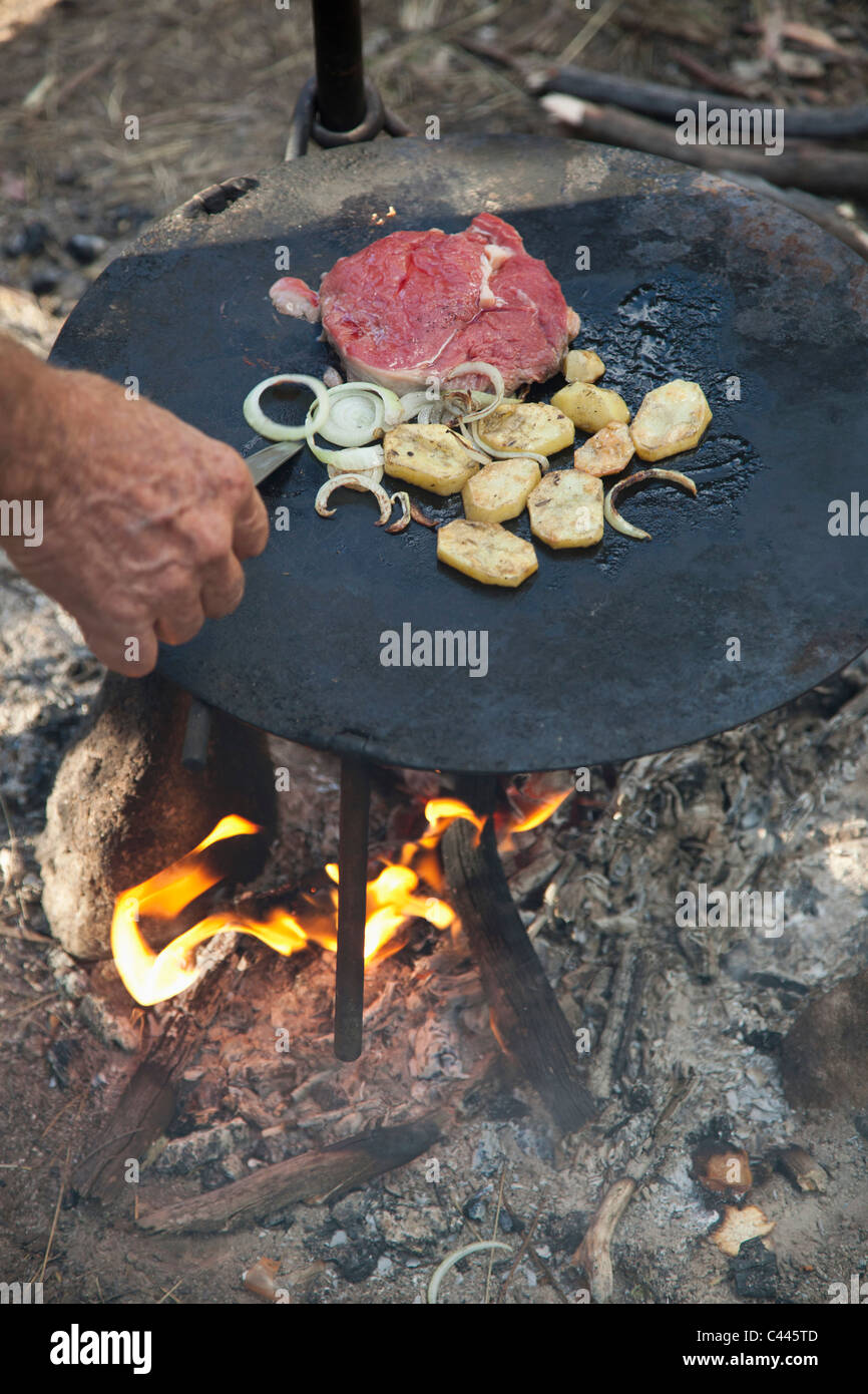 Detail eines Mannes Kochen über dem Lagerfeuer Stockfoto