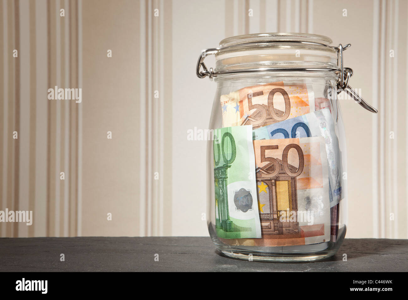 Geld Glas mit Euro-Banknoten innen auf einem Tisch Stockfoto