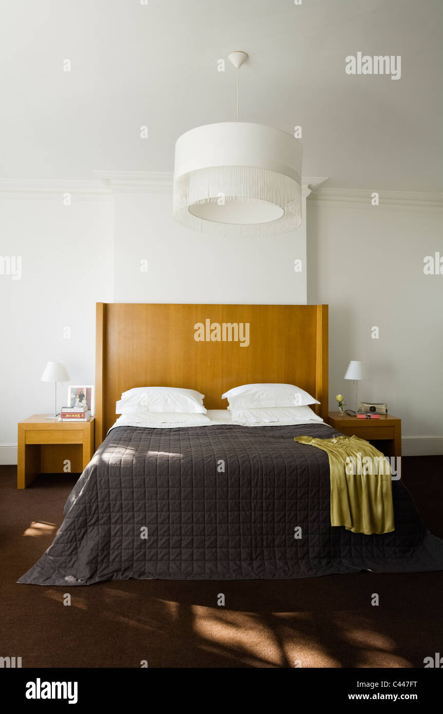 Doppelbett mit hölzernen Kopfteil und Quilt in weiße Schlafzimmer mit großen hellen Farbton Stockfoto