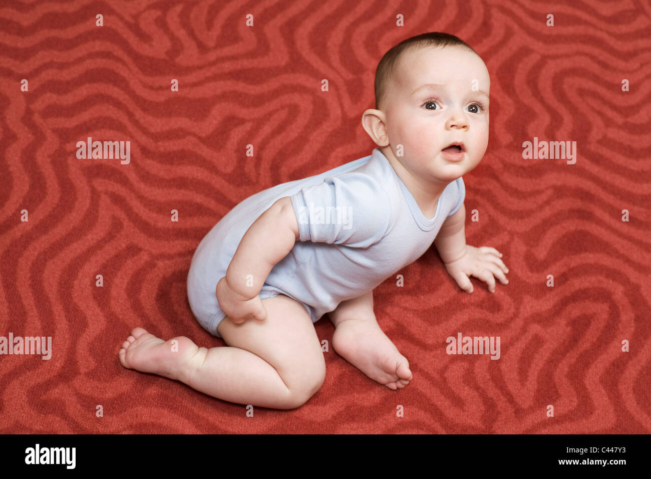 Einen kleinen Jungen auf einem gemusterten Teppich liegend Stockfoto