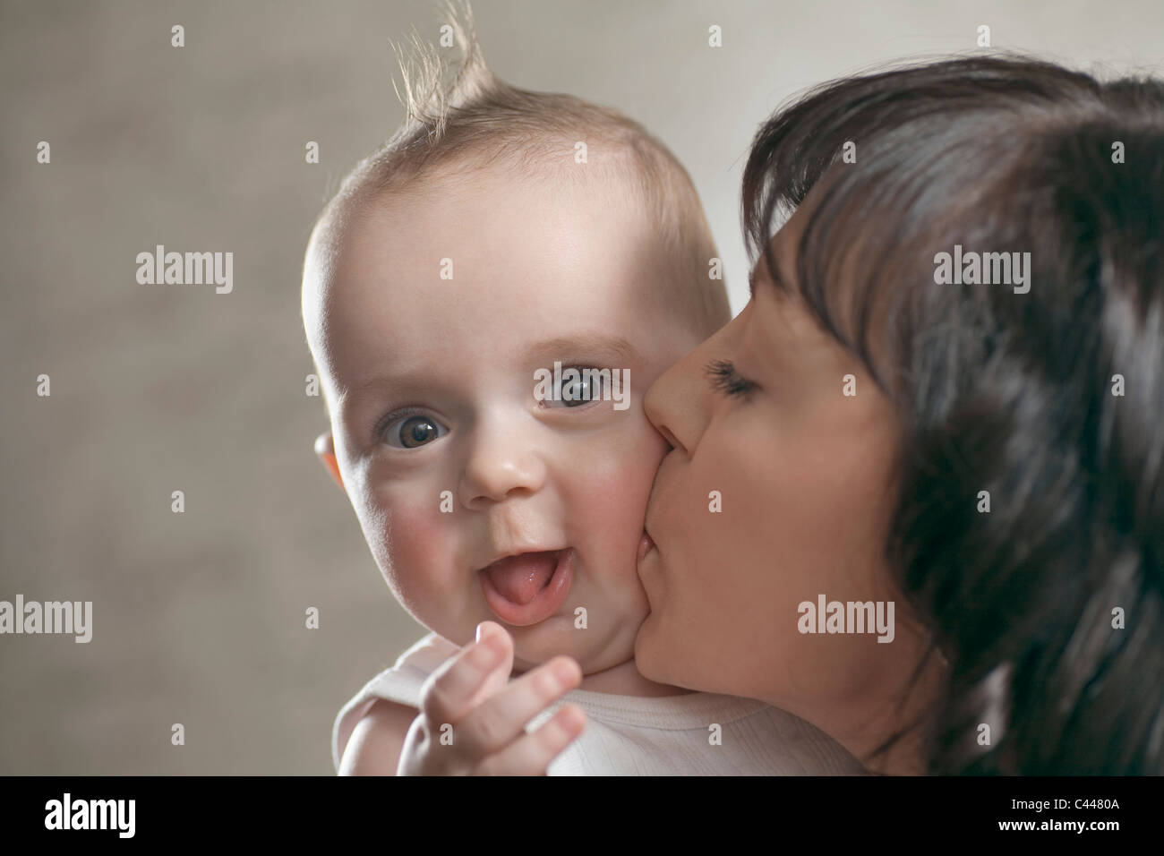 Ein überrascht Baby immer von seiner Mutter geküsst Stockfoto