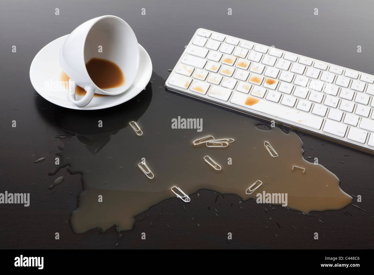 Eine Tasse Kaffee verschüttet auf einer Computertastatur Stockfoto