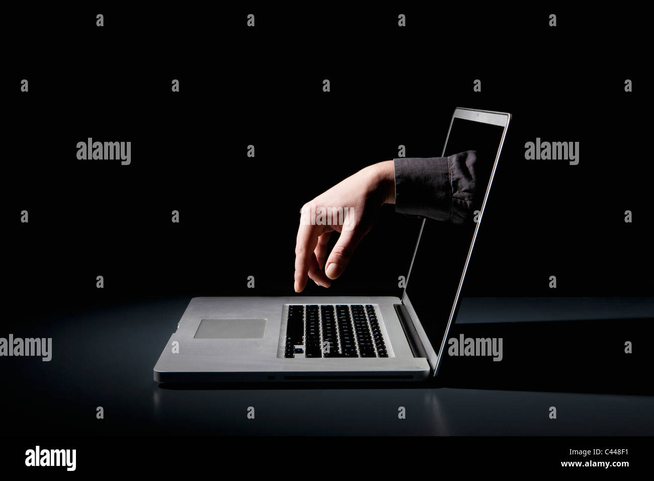 Eine Hand greift über ein Notebook, das über die Tastatur eingeben Stockfoto