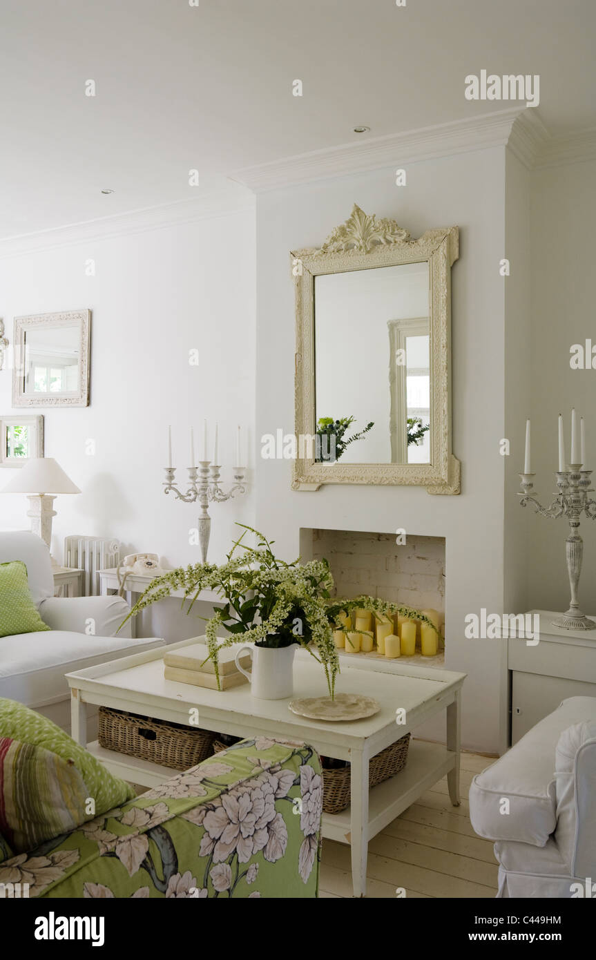 Weiße Wohnzimmer mit Couchtisch, Spiegel und floral gemusterten Sofa. Stockfoto