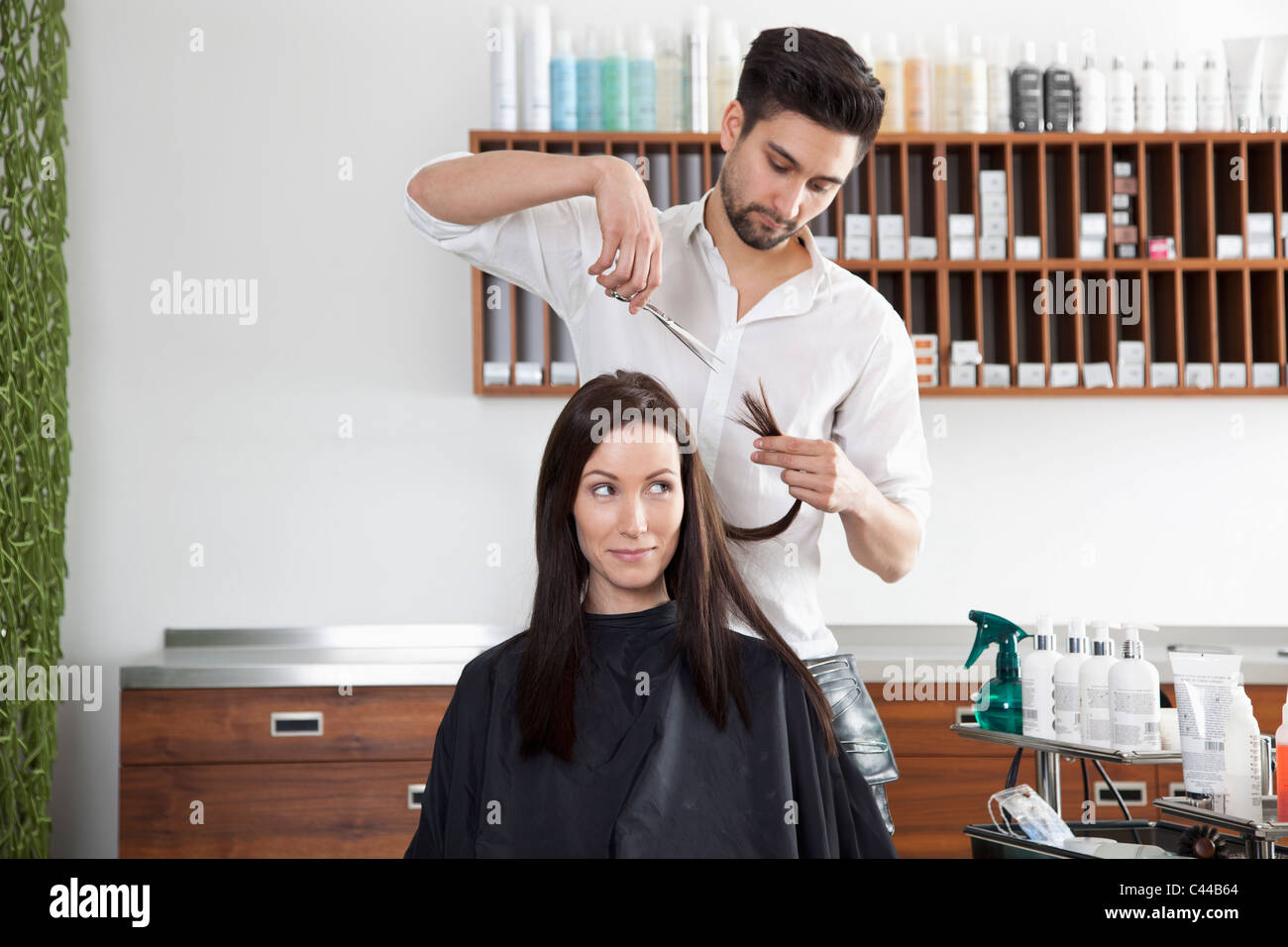 Eine Frau, die ihr Haar schneiden von einem männlichen Friseur Stockfoto