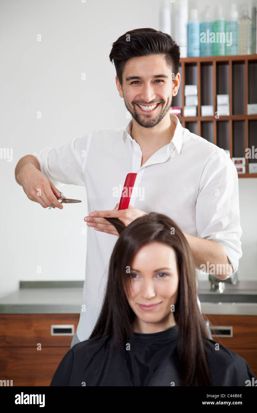 Eine fröhliche männliche Friseur eine Frau Haare schneiden Stockfoto