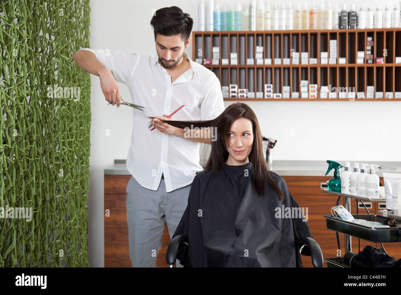 Eine Frau, die ihr Haar schneiden von einem männlichen Friseur Stockfoto