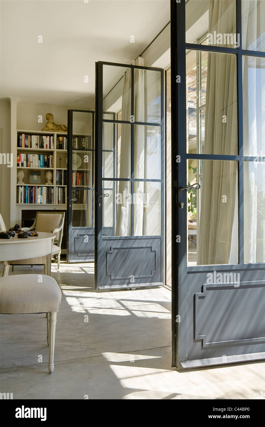 Wohnzimmer mit Bücherregal und drei geöffneten Glastüren verglaste Stockfoto