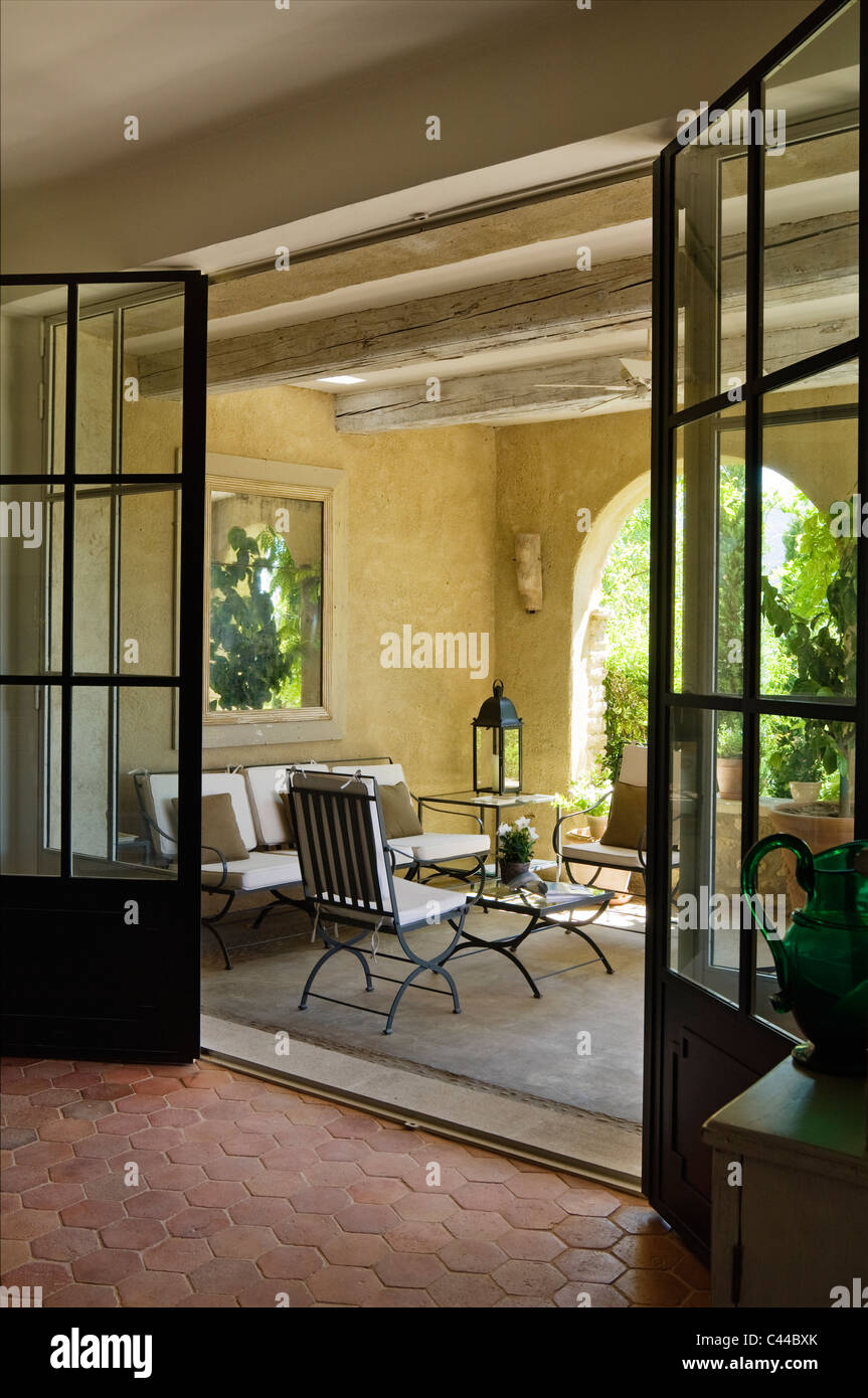 Blick durchs Glas verglaste Doppeltür heraus auf Loggia mit Balkendecke, Laternen und outdoor-Möbel Stockfoto
