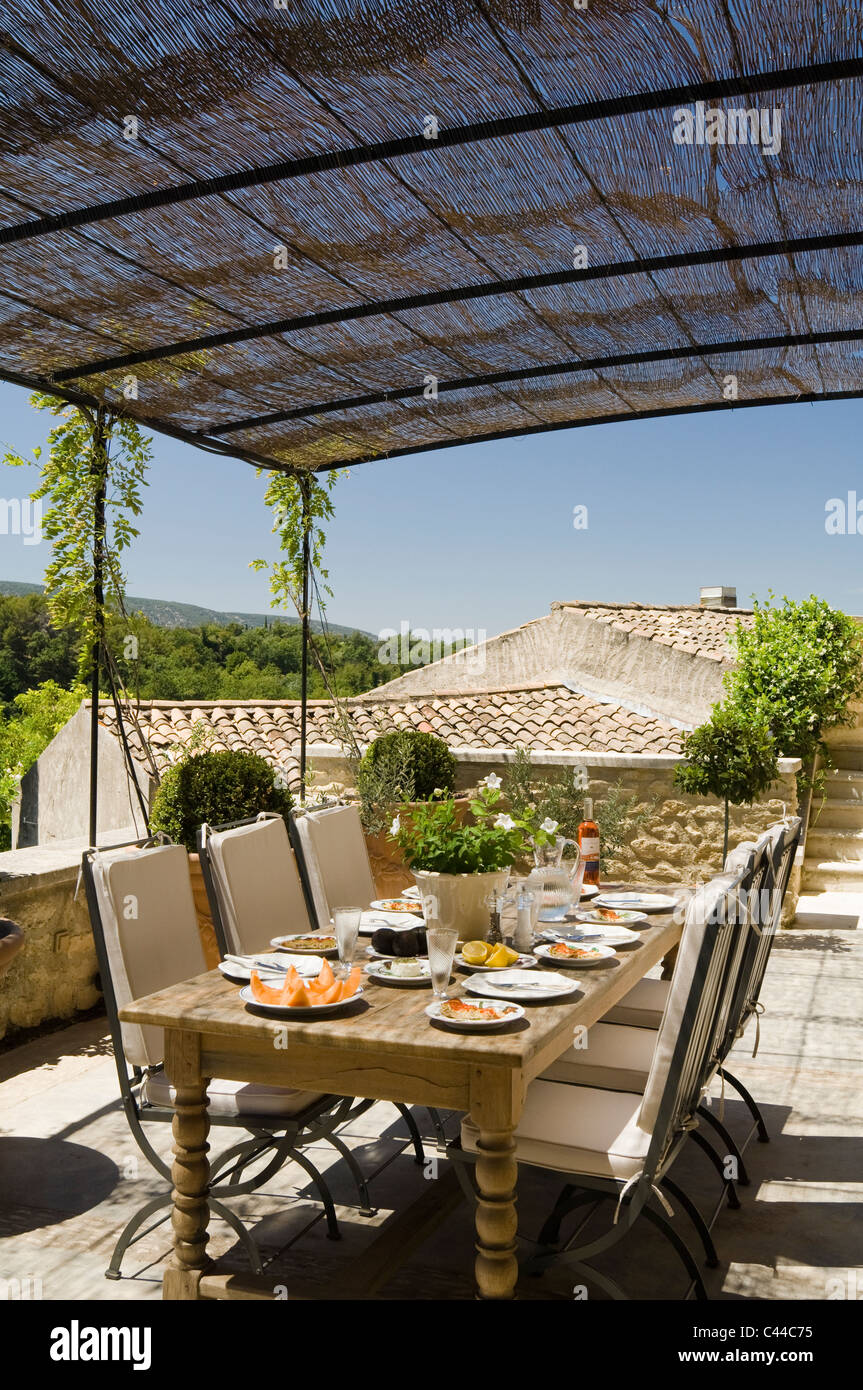 Esstisch mit Stühlen auf steinernen Terrasse mit Markise von Provence-Dorfhaus Stockfoto