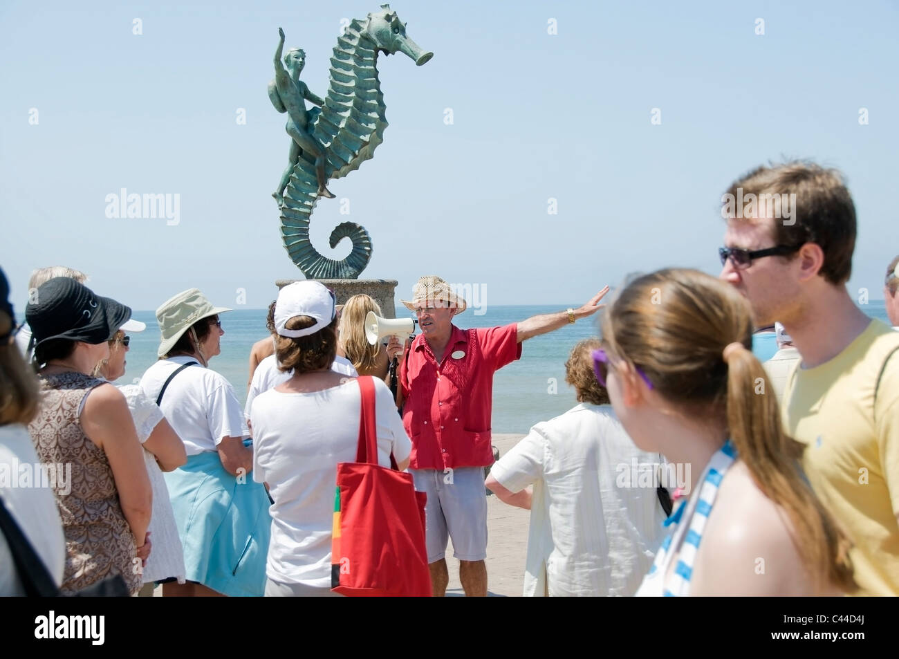 Eine Tourguide befasst sich eine Menge von Touristen vor "The Sea Horse" Skulptur auf dem Malecon in Puerto Vallarta, Mexiko. Stockfoto